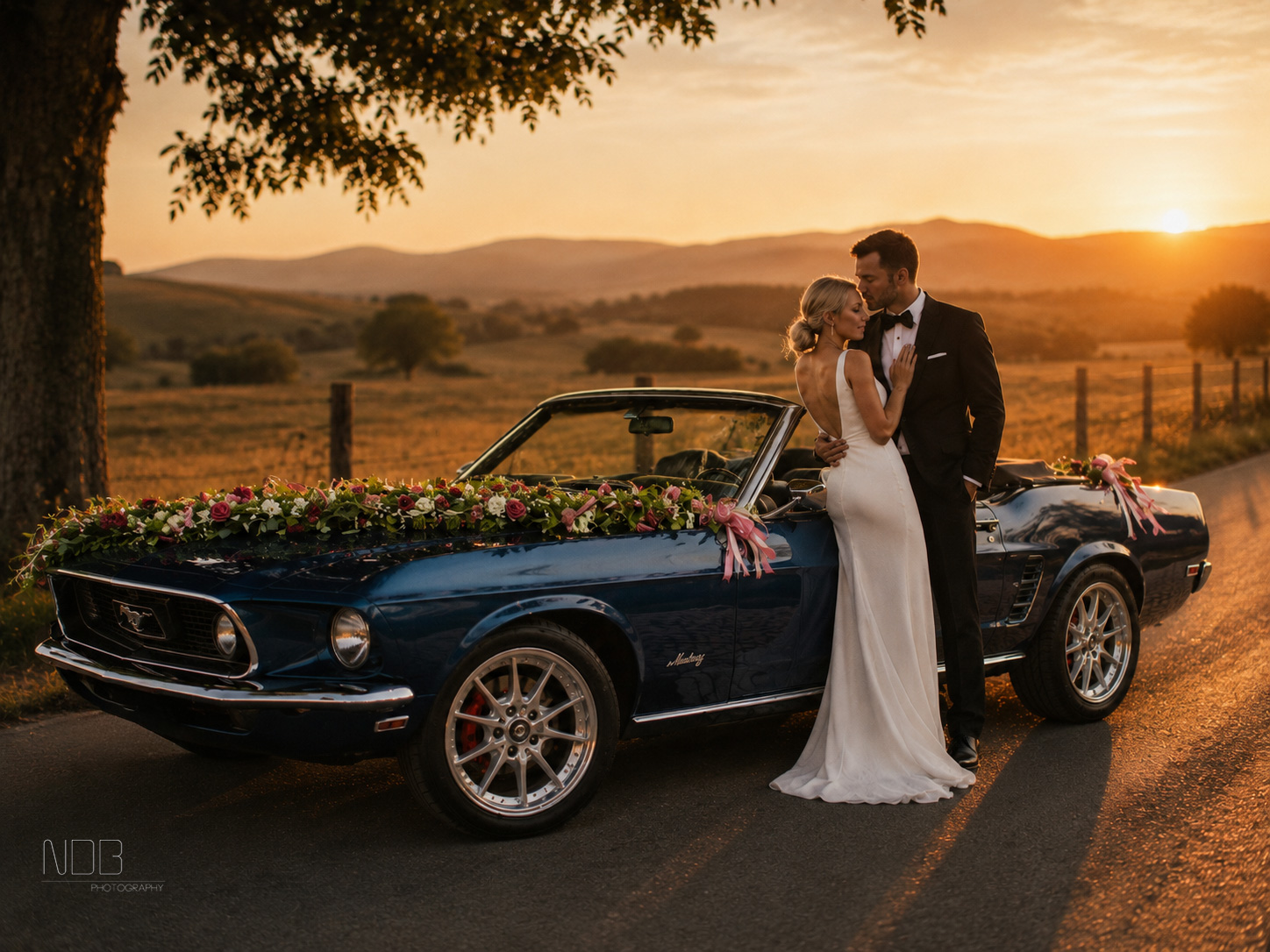 Brautpaar am geschmückten 1969 Ford Mustang Cabrio bei Sonnenuntergang